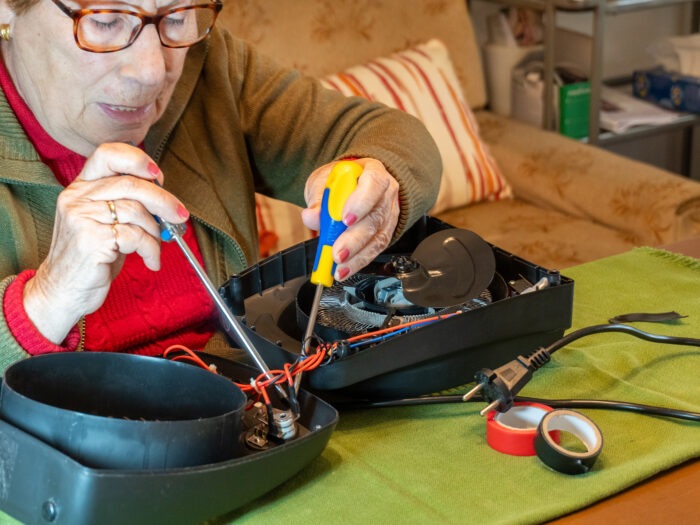 Senior woman fixing a small household appliance at home