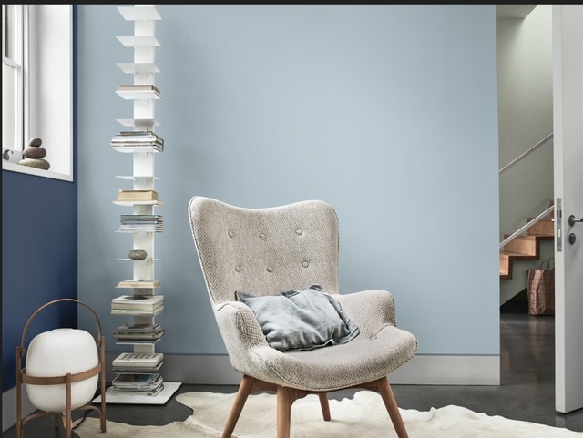 blue grey living space with grey pincushion chair, floor lamp and blue walls