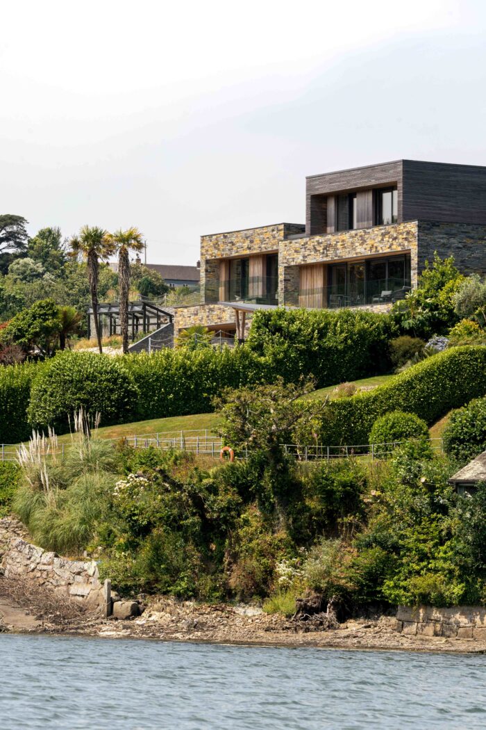 The exterior is clad in local stone and timber with terraced gardens down to the river. 