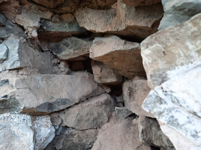 Inside the damaged stone wall of the house