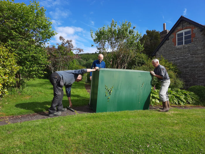 Three men moving an old oil tank