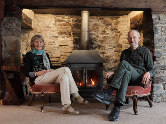 Couple sitting in front of a fire in an inglenook fireplace 